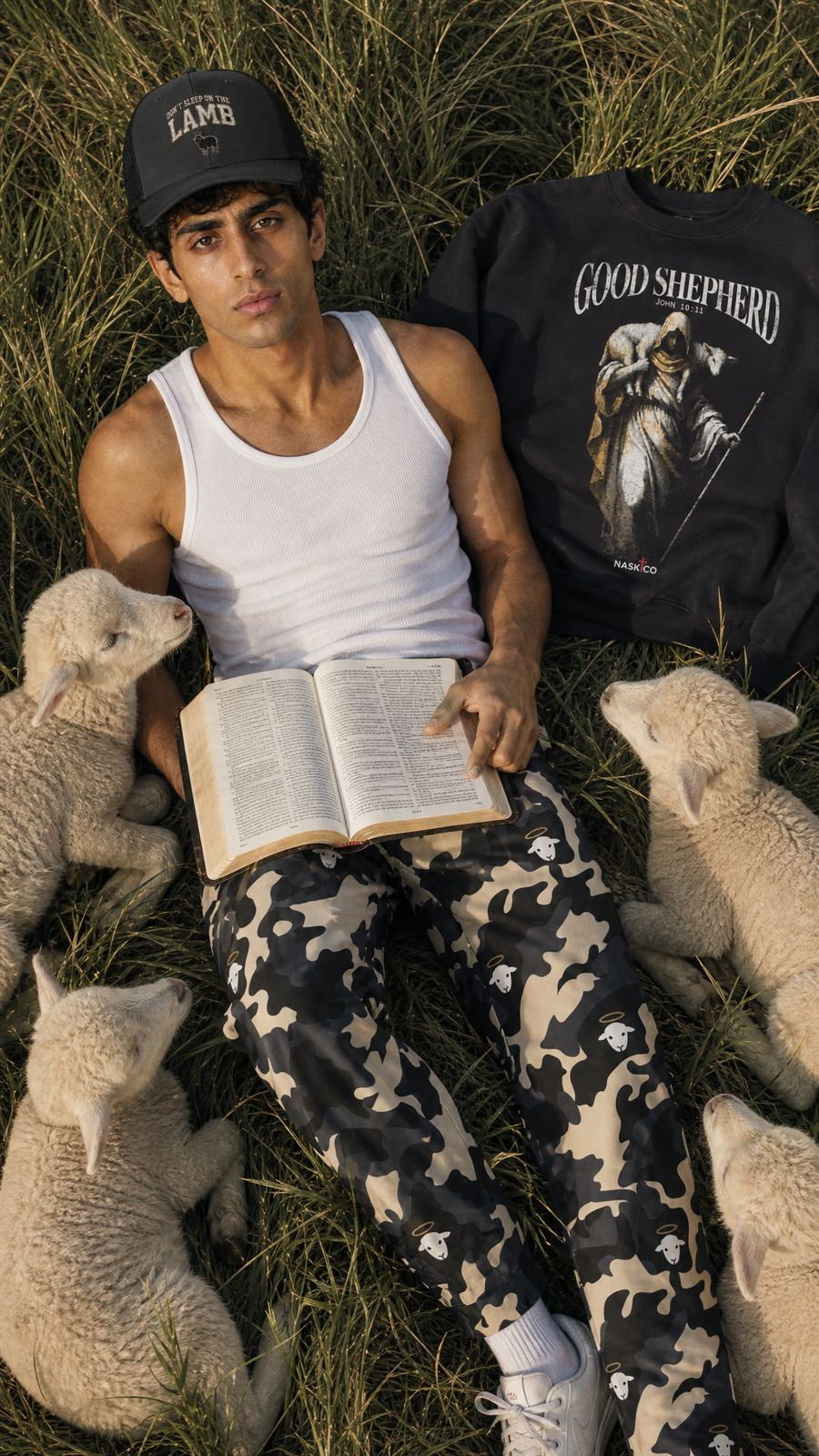 A man reading the Bible in grass with lambs and NaskiCo garments