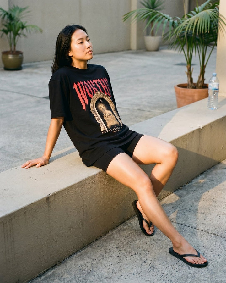 Model in the NaskiCo Worthy Christian streetwear tee and thongs in the summer sun, Revelation 5:12